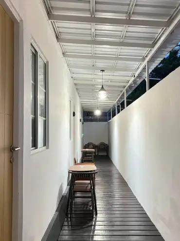 Koridor santai outdoor Wisma Apollo dengan meja dan kursi